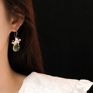 Détail de boucles d'oreilles papillon en zircon avec cristal goutte vert sur mannequin
