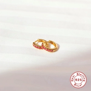 Detailed macro of gold plated S925 sterling silver huggie earrings with red cubic zirconia