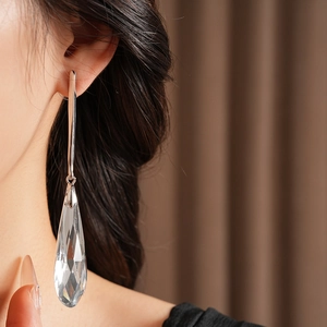 Close-up of model wearing a faceted crystal water drop earring with silver hook