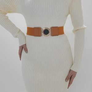 Detail of orange elastic waist belt featuring a round metallic buckle and black texture