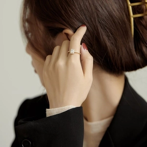 Elegant gold square halo ring with side stones worn on a finger for a luxury look
