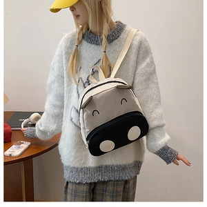 Detail of the cute cartoon cow canvas backpack worn by a toddler model for outdoors