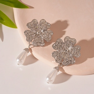 Macro detail of silver floral earring with sparkling crystals and drop pearl pendant