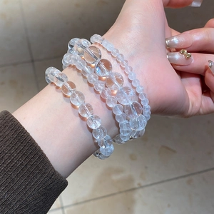 Detailed layering of multi-sized clear quartz beaded bracelets on a female wrist