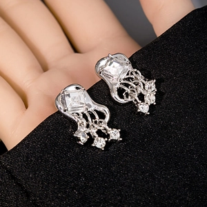 Macro shot of silver jellyfish earrings with cubic zirconia on black fabric