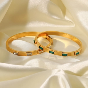 Bracelets en acier titane avec zircons blancs et verts sur un tissu en soie beige doux