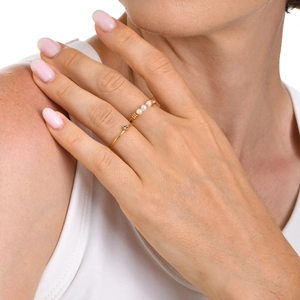 Close-up of gold-plated twisted rings featuring a pearl row and minimalist crystal setting