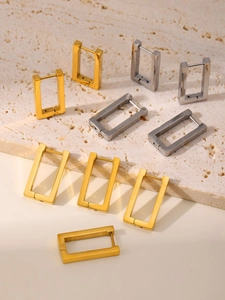Detail of geometric rectangular hoop earrings in gold and silver finish on stone