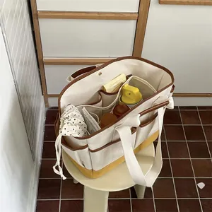 Detail view of multi-pocket canvas mommy bag interior with leather trim and storage space