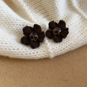 Close-up of velvet brown flower earrings with leopard print center on knit fabric