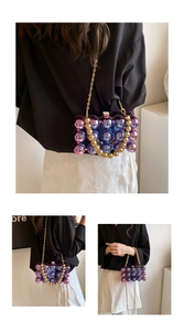 Detail of gradient blue-purple acrylic bag with golden chain and beaded handle