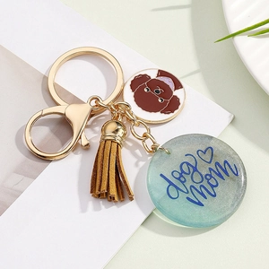 Detail of dog mom keychain with poodle charm, brown tassel, and blue engraved pendant