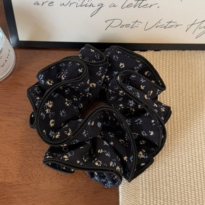 Detail of navy blue floral scrunchie on a wooden desk with elegant lifestyle accessories