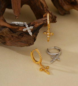 Close-up detail of silver and gold cross drop earrings with shimmering micro-pave stones
