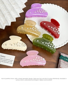 Detailed set of six colorful acetate hair claws with inlaid pearls on a white tray