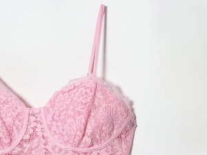 Close-up detail of pink lace camisole showing fine floral patterns and slim straps
