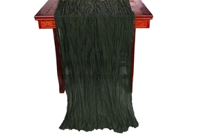 Detailed texture of dark green crinkled gauze table runner over wooden display