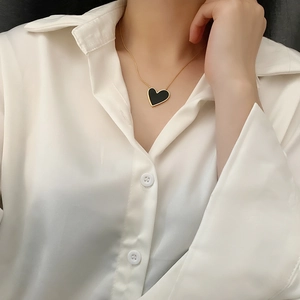 Close-up of heart-shaped black enamel pendant on a fine golden chain necklace