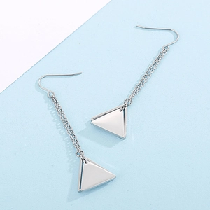 Macro shot of silver geometric triangle earrings with long chain tassels and hooks