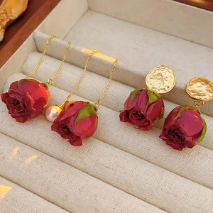 Gros plan de boucles d'oreilles rose rouge en versions puces et pendantes avec perles