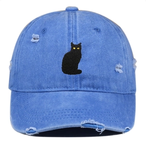 Close-up of distressed washed blue denim baseball cap featuring black cat embroidery