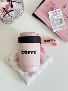 Detail of pink coffee cup with a textile carry strap and matte finish on white base