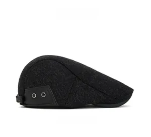 Detail of dark grey herringbone wool newsboy hat featuring leather patch and metal eyelets