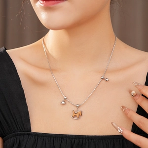 Détail du collier argenté avec pendentif cheval à bascule et grelots porté par un mannequin