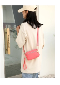 Close-up of vibrant pink mini crossbody bag with gold zippers and detachable strap