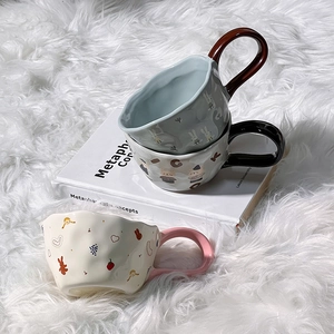Detailed view of ceramic mugs with bear and rabbit prints on a white plush rug