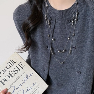Detail of silver grey double layer long pearl necklace on grey knit sweater