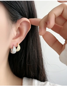 Close-up of gold and silver micro-paved cubic zirconia hoop earrings on ear