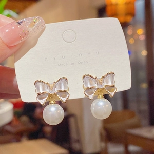 Macro detail of sweet bowknot pearl earrings with sparkling cubic zirconia on display card