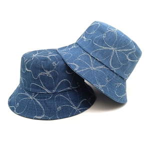 Two denim bucket hats in dark blue with white floral pattern on a clean white background