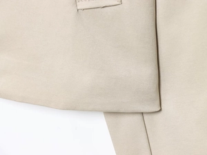 Dettaglio ravvicinato del tessuto twill beige del trench che mostra trama e cuciture