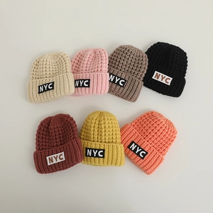 Close-up of chunky knit baby beanies in seven colors featuring NYC letter patches