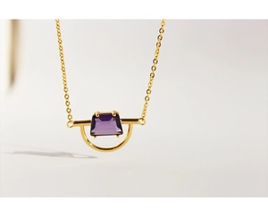 Detail of a gold-plated brass necklace featuring a purple trapezoidal zircon pendant