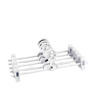 Set of five white adjustable plastic pant hangers with non-slip clips on a white background