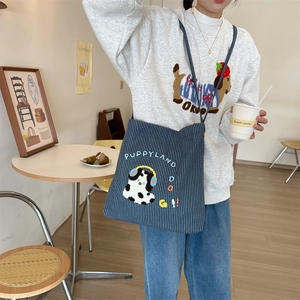 Navy striped canvas crossbody bag featuring 3D puppy embroidery in a cafe setting