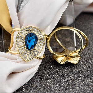 Detailed view of golden scarf ring with blue teardrop crystal and sparkling rhinestones