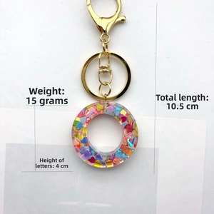 Detailed view of resin letter keychain with pink heart sequins and size specifications