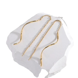 Elegant gold S-curve threader earrings on a white stone background for a minimalist style