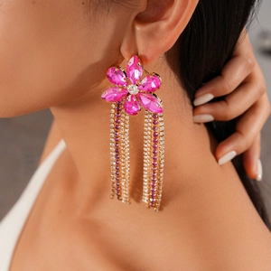 Gros plan détaillé de boucles d'oreilles fleur avec strass roses et franges dorées