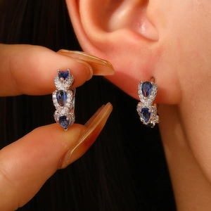 Macro detail of blue pear-cut zircon earrings set in polished silver metal on model
