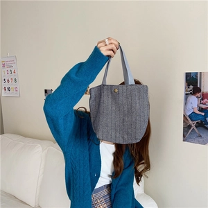 Detail of minimalist wool bento bag with black and white herringbone pattern and snap closure