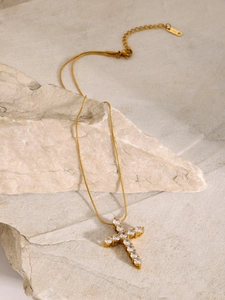 Detail of 18k gold plated cross pendant with white zircon stones on natural stone