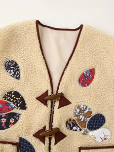 Detailed macro shot of beige sherpa vest featuring vintage floral patches and horn buttons