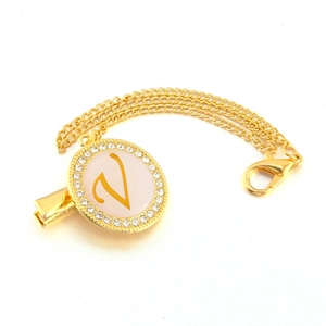 Detailed view of golden pacifier clip with rhinestone letter V on white enamel charm
