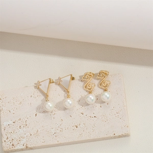 Minimalist gold triangle earrings and cloud-shaped pearl pendants on a textured stone base