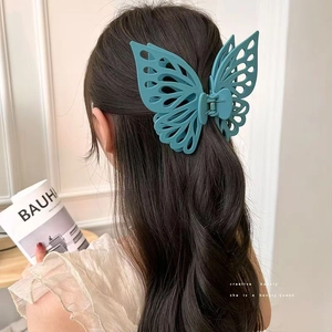 Detail of a large matte blue butterfly hair claw clip worn on a model's hair